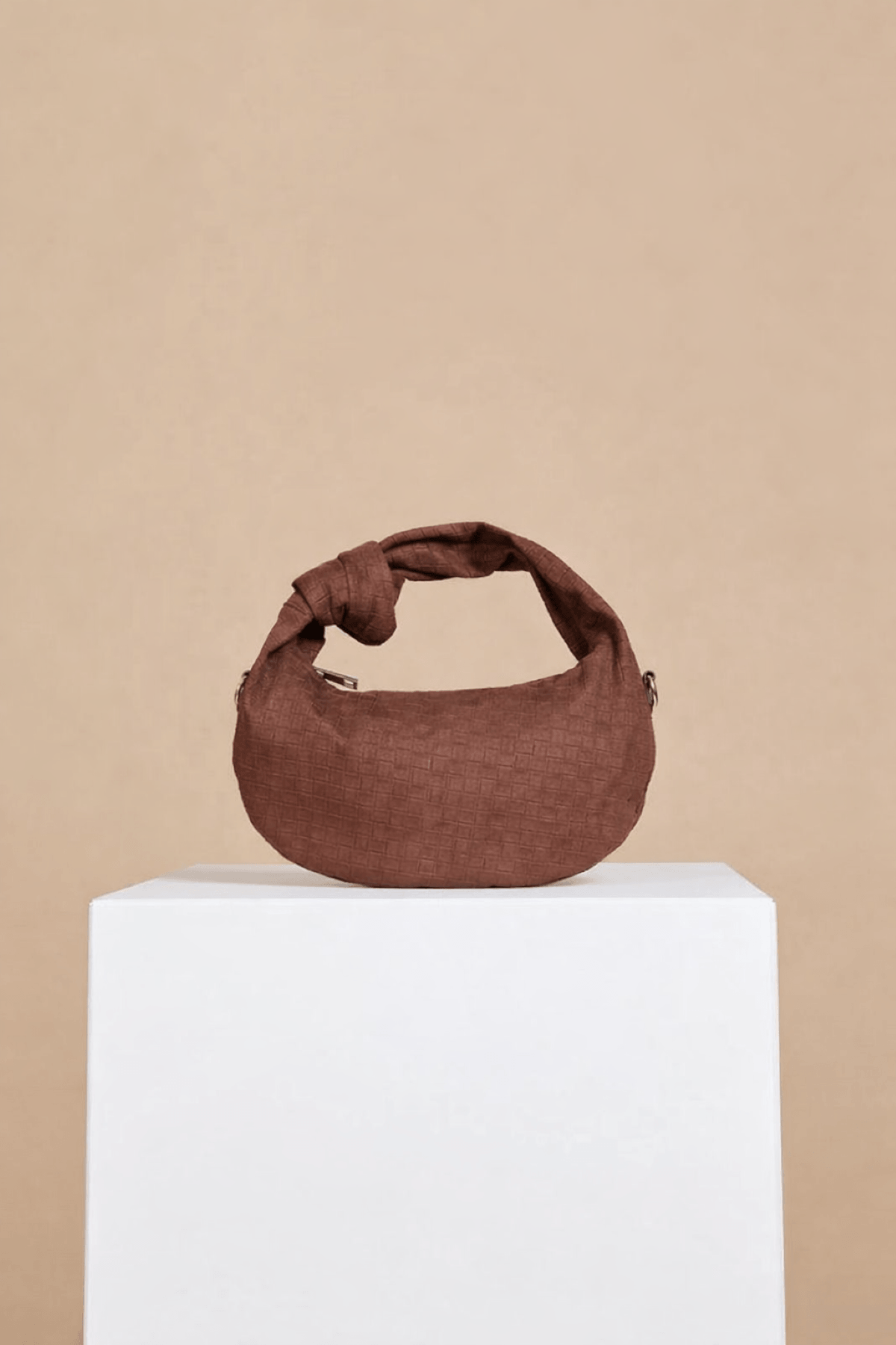 Chocolate Faux Suede Woven Emboss Grab Bag with knot handle and embossed pattern on display.