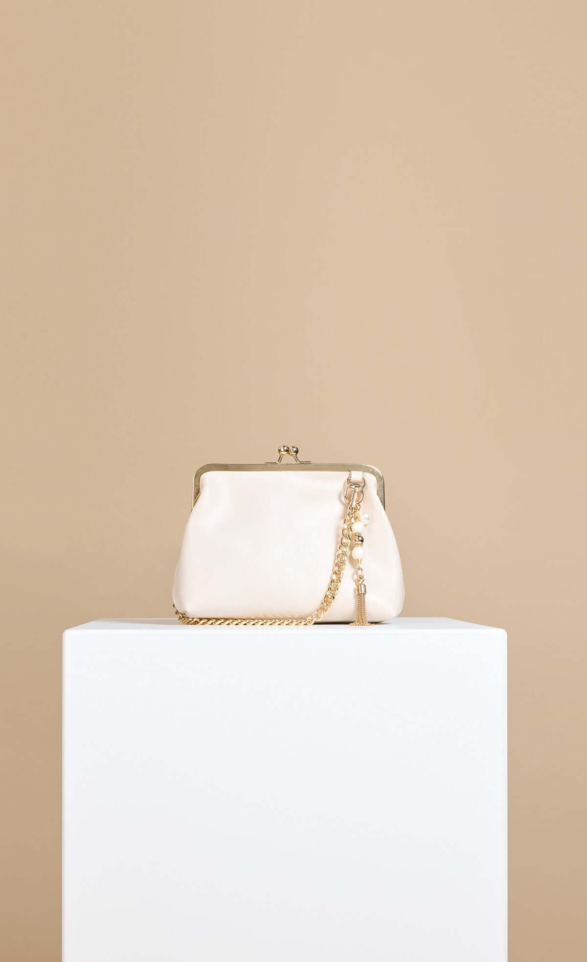 Ecru Faux Leather Metal Frame Shoulder Bag with chain strap and pearl charm on display.