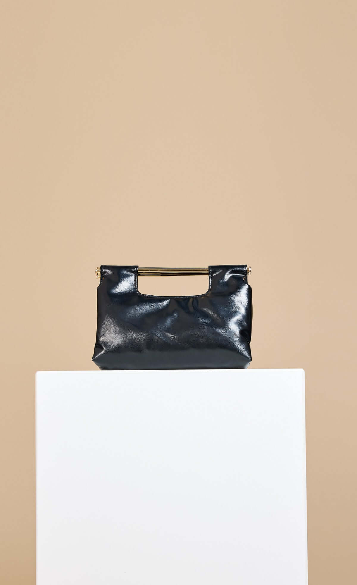 Black Metal Bar Clutch Bag in soft faux leather with shoulder strap against a minimal backdrop.
