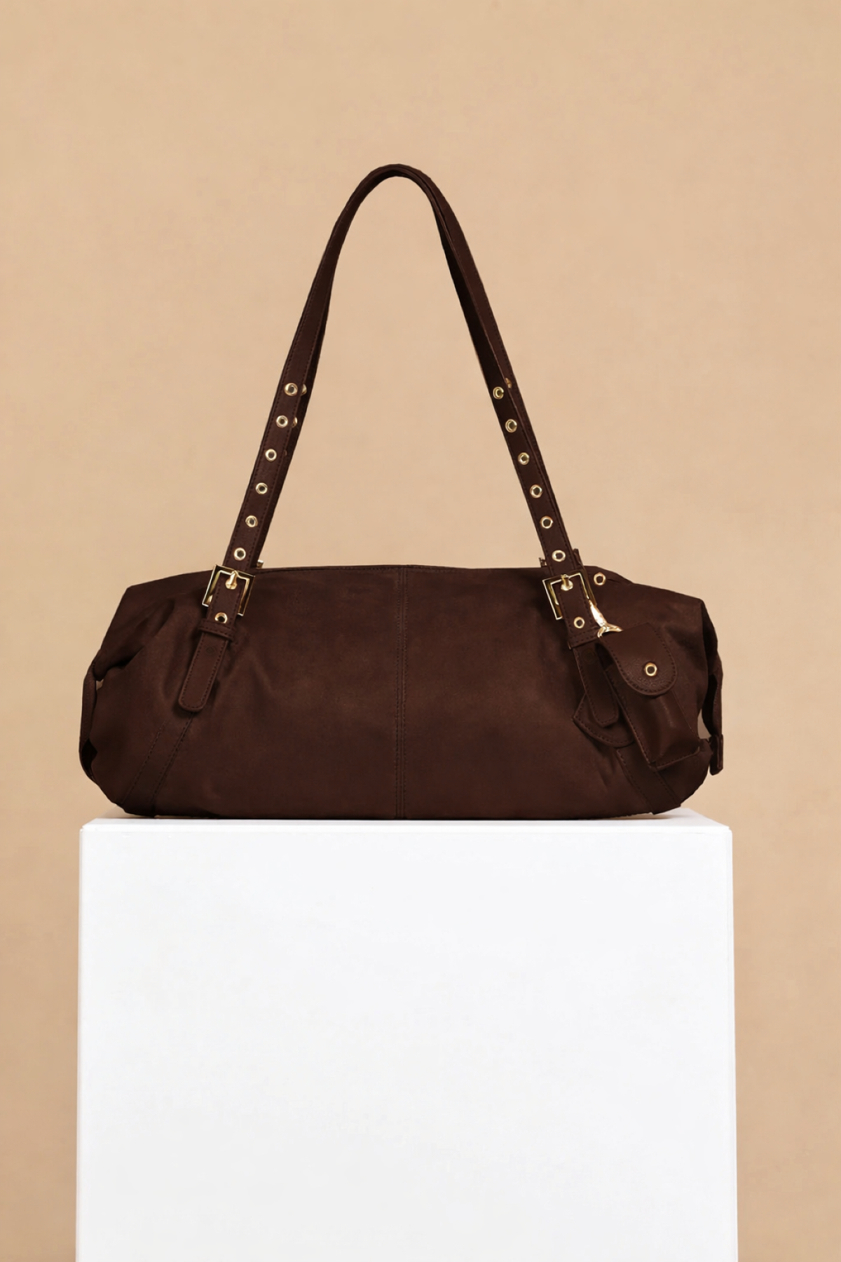 Chocolate Faux Suede Shoulder Bag with eyelet strap and gold metal trims on display.