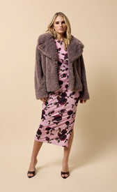 Model wearing a mink faux fur jacket over a pink floral dress, showcasing luxe winter style.