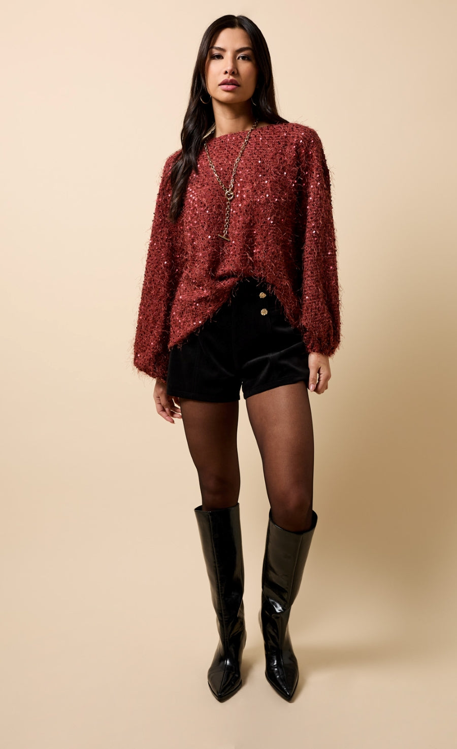 Model wearing Paloma Black Velvet Button Detail Shorts paired with a cozy red sweater and stylish knee-high boots.