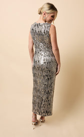 Model showcasing the back of the Solara Silver Sequin Knot Detail Midaxi Dress against a beige background.