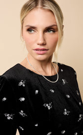Model wearing the Sondra Black Velvet Embroidered Mini Dress with elegant embroidery and a silver necklace.