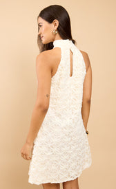 Solenne Cream Textured Halterneck Mini Dress showcasing elegant A-line design from the back on a model.
