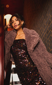 Meliora Multi Sequin Bandeau Midaxi Dress worn under a cozy coat, showcasing a shimmery black sequin design for a glamorous look.