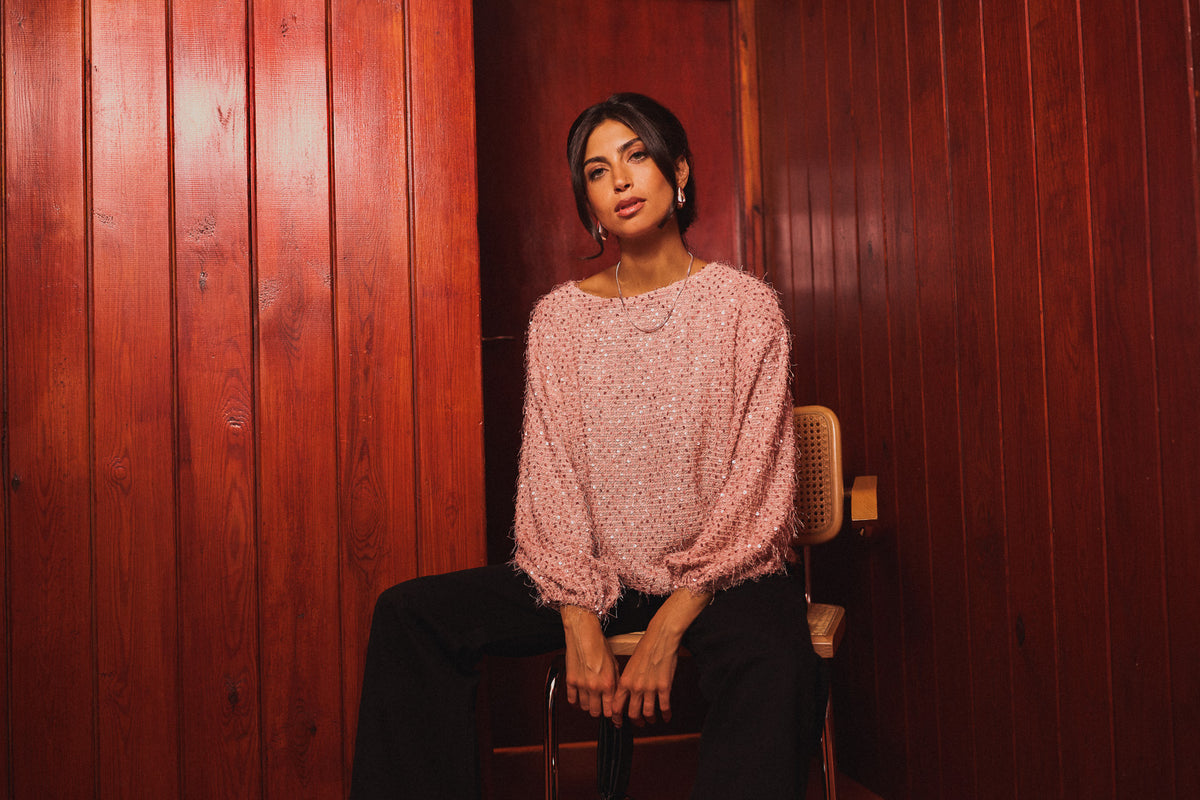 Model wearing a pink knit jumper and black trousers