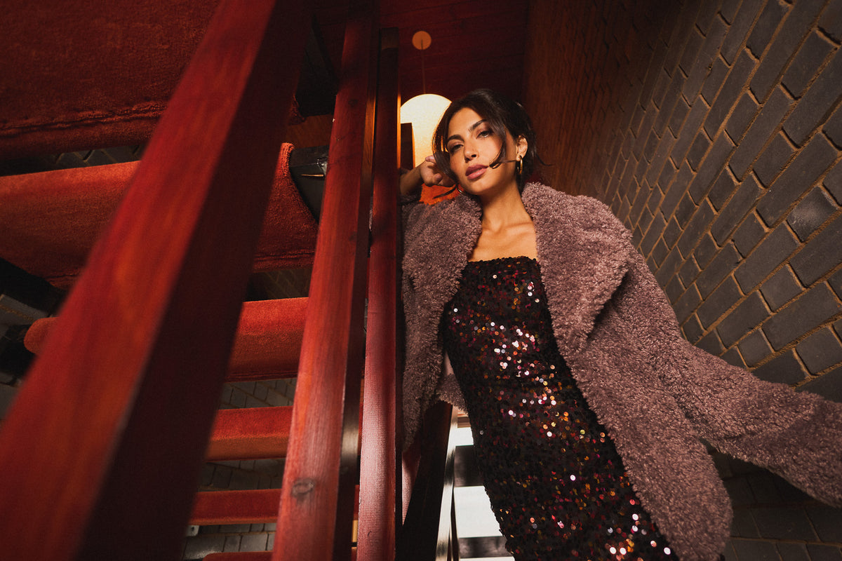 Model wearing a textured mauve coat over a sequin dress