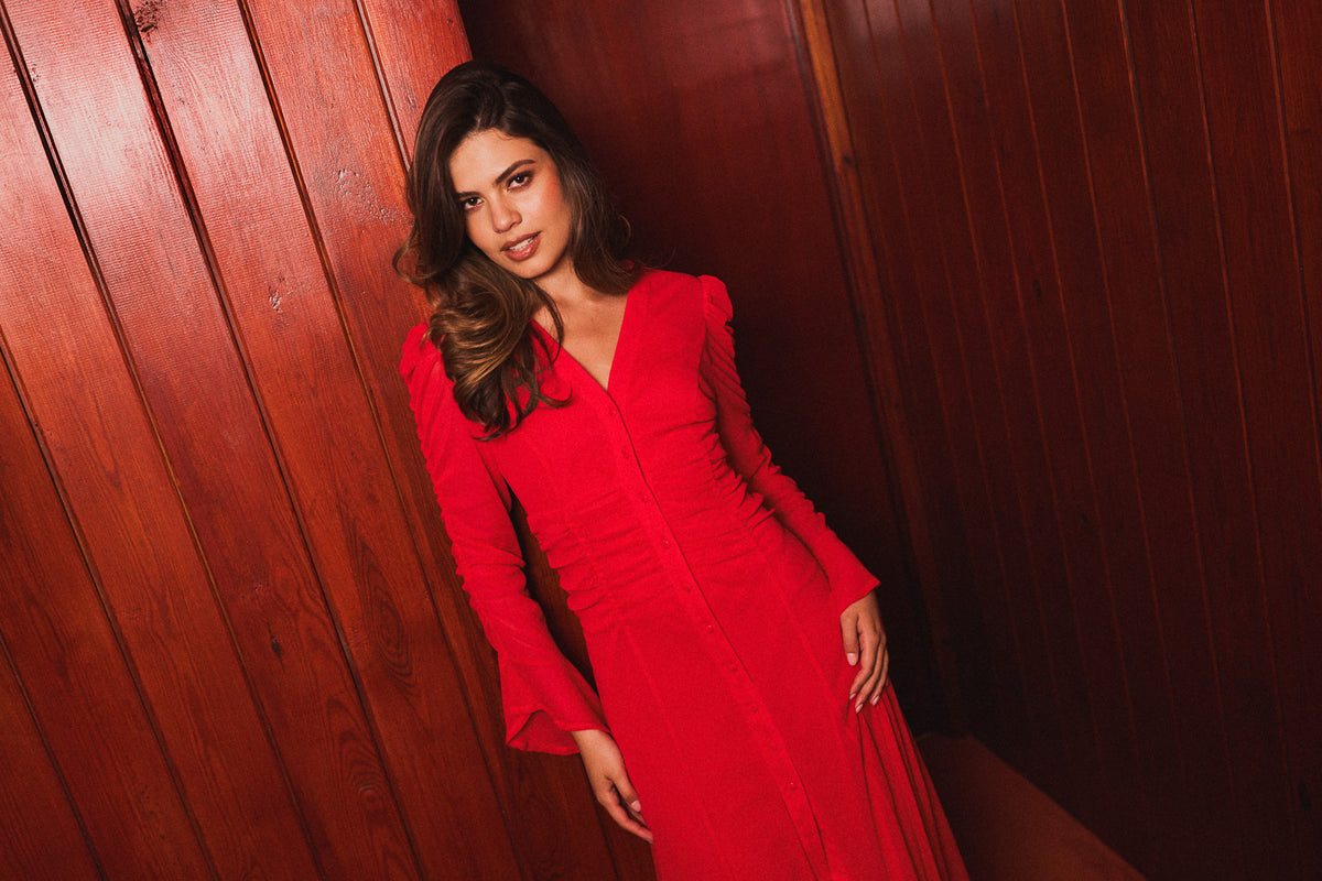 Model wearing a red midi dress against wood panelling
